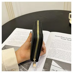 Portafoglio lungo nero con zip da donna, grande borsa a mano con dettagli metallici.