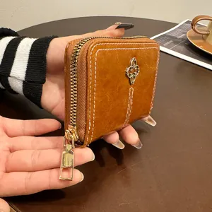 Portafoglio corto da donna in morbida pelle marrone con chiusura zip e dettaglio metallico.