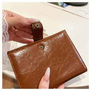 Detaillierte Nahansicht des braunen, glänzenden Leder-Passhalters mit praktischem Druckknopf.