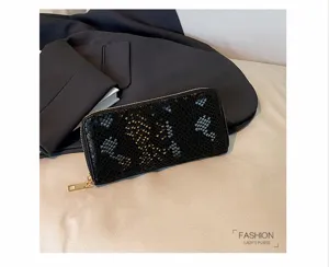 Detail shot of a stylish black snakeskin long zipper wallet for women with golden hardware.