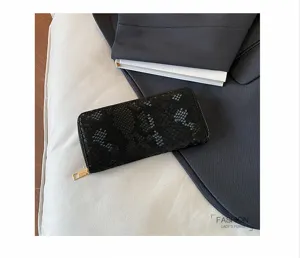 Close up detail of black snakeskin long wallet with gold zipper, elegant evening clutch design.