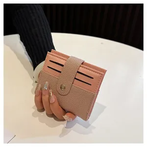 Primo piano di un mini portacarte minimalista con chiusura a pressione e fessure rosa.