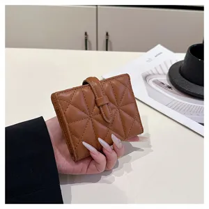 Primo piano di un portafoglio corto trapuntato marrone in PU con chiusura, posato sul tavolo.