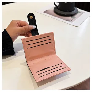 Dettaglio di portafoglio porta carte compatto rosa e nero con slot interni e chiusura a bottoni.