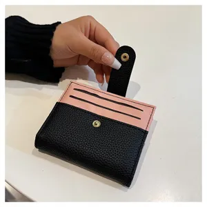 Vista di dettaglio di un mini portacarte bicolore rosa e nero con bottone a pressione.