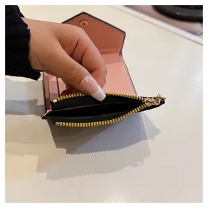 Gros plan sur les détails d'un petit portefeuille court en cuir PU avec une poche zippée.