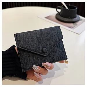 Gros plan d'un mini porte-monnaie enveloppe en cuir PU noir, montrant la texture et le bouton.