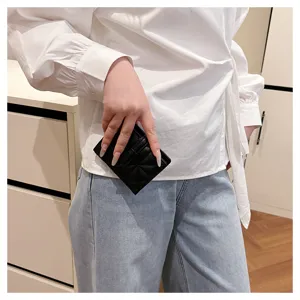 Primo piano di un mini portafoglio nero trapuntato in ecopelle PU tenuto in mano.
