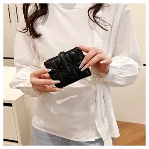 Primo piano di un portafoglio corto nero trapuntato da donna in ecopelle con cinturino.
