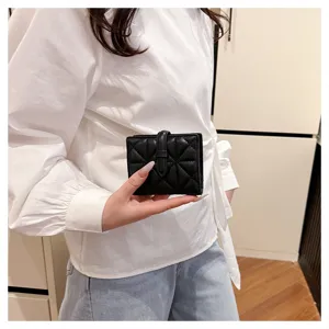 Dettagliato primo piano di un elegante portafoglio compatto nero in ecopelle trapuntata.