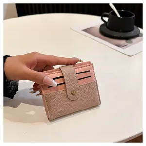 Primo piano di un porta carte minimalista rosa e kaki con chiusura a bottone a pressione.