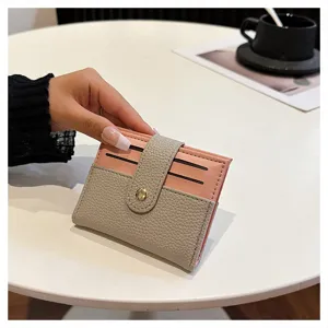 Primo piano del porta carte in pelle rosa e grigia, con chiusura a bottone a pressione.