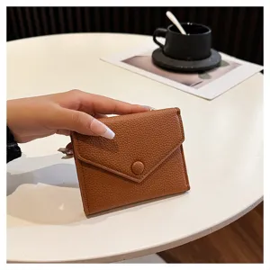 Vue détaillée d'un petit portefeuille court pliable en cuir PU marron sur une table.