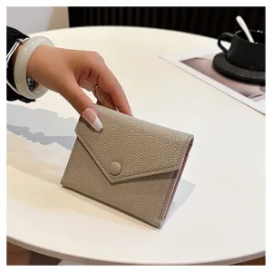 Gros plan d'un portefeuille enveloppe minimaliste en cuir PU gris, fermeture pression.