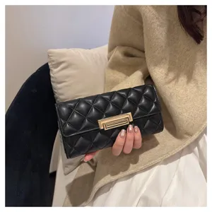 Primer plano del monedero largo acolchado negro con textura de cuero suave y cierre dorado.