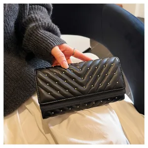 Primo piano del portafoglio lungo nero con impuntura chevron e borchie metalliche.