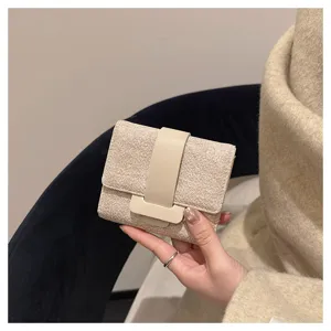 Compact trifold women wallet with textured fabric and smooth leather strap closure detail