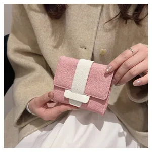 Pink tri-fold wallet close-up, compact size with contrast white leather strap detail.