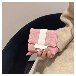 Detail shot of a chic pink trifold mini wallet with a white vertical strap and snap closure.