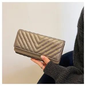Elegante portafoglio lungo da donna grigio metallizzato con trapuntatura e borchie dorate.