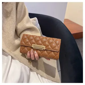 Vista detallada del elegante bolso de mano largo de cuero acolchado marrón con broche.