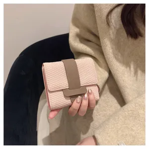 Pink woven tri-fold women wallet with brown strap snap closure, compact daily purse detail view.