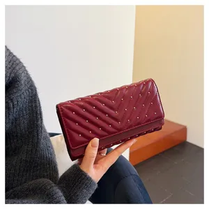 Primo piano di un elegante portafoglio bordeaux con cuciture trapuntate e borchie d'oro.
