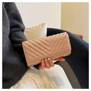 Dettaglio di portafoglio lungo trapuntato rosa con cuciture a chevron e borchie dorate eleganti.