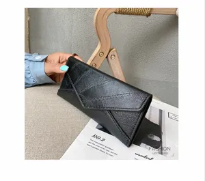 Detailed shot of black long leather envelope wallet held by hand with magazine prop.