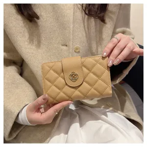 Vue détaillée de petit portefeuille matelassé pour femme en cuir beige avec fermoir en métal.