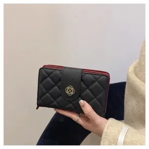 Élégante porte-monnaie court matelassé noir pour femme avec doublure rouge et fermoir trèfle doré.
