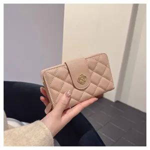 Détail de portefeuille court matelassé rose, montrant le motif losange et fermoir doré.