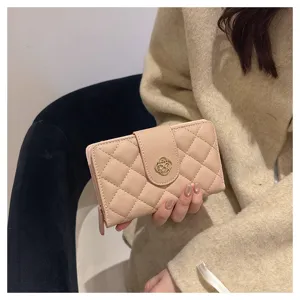 Gros plan détaillé du portefeuille court matelassé rose avec fermoir doré, design élégant.