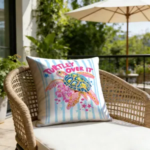 Outdoor patio detail view featuring a colorful turtle patterned decorative pillow on a chic wicker armchair.