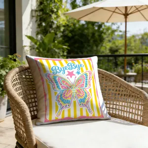 Outdoor patio pillow detail featuring vibrant retro butterfly graphic and cute text, resort vibe.