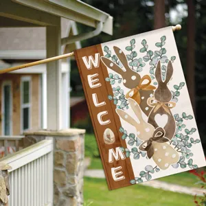 Detailed view of Easter garden flag with cute bunnies and welcome sign hanging outside home.