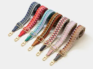 Gros plan de lanières de sac tissées colorées avec boucles métalliques dorées réglables.