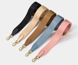 Vista detallada de correas de bolso anchas tejidas multicolor con extremos de cuero y ganchos.