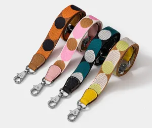 Detailed view of colorful polka dot bag replacement strap with metal swivel hooks and leather ends.
