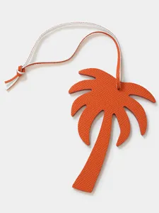Dettaglio in primo piano del ciondolo a forma di palma in pelle arancione con cinturino.