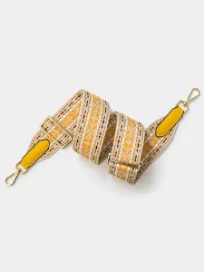 Adjustable wide woven bag strap detail, golden metal hardware and yellow leather accents.