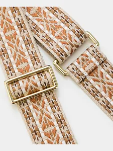 Detailed shot of the woven wide bag strap with ethnic geometric pattern and gold metal hardware.