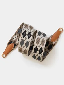 Detailed shot of wide polyester replacement bag strap with argyle pattern and leather ends.