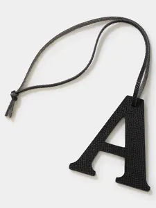 Black leather uppercase letter A pendant detail shot, stylish handbag key and car charm accessory.