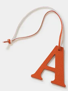 Leather letter A charm detail close-up showing fine texture and orange color for bag and keys.