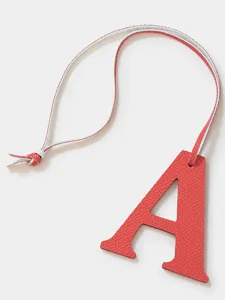 Red leather letter A charm closeup showing textured cowhide and delicate hanging strap.