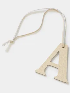 Beige leather letter A bag charm keychain, minimalist luxury style accessory for bags.
