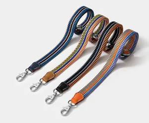 Detailansicht von bunten gewebten Ersatz-Taschenriemen mit Lederlaschen und Metallhaken.