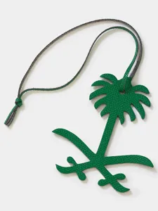 Green leather palm tree bag charm detail, premium textured leather key ring pendant closeup.