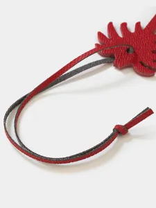 Red leather palm tree bag charm detail close-up, luxury style handbag pendant accessory for keys.
